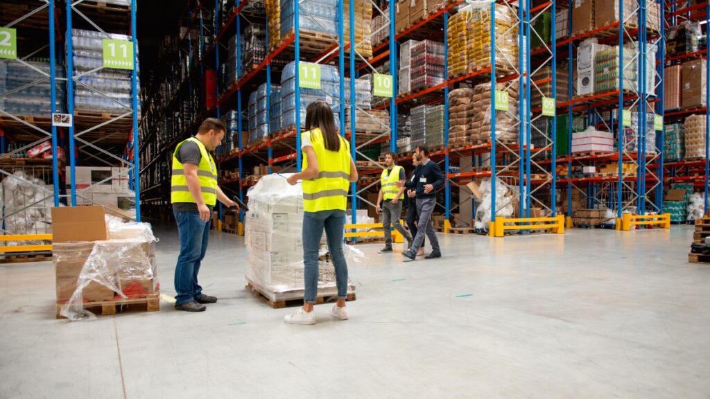 Warehouse workers inspecting shrink-wrapped pallets