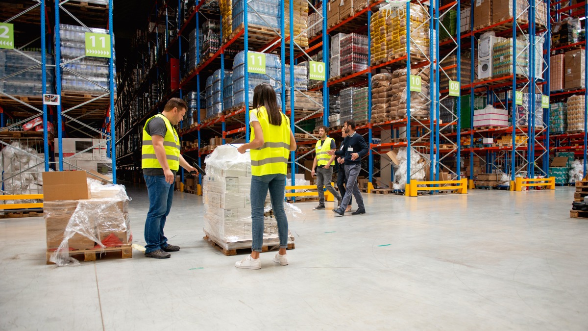 Warehouse workers inspecting shrink-wrapped pallets