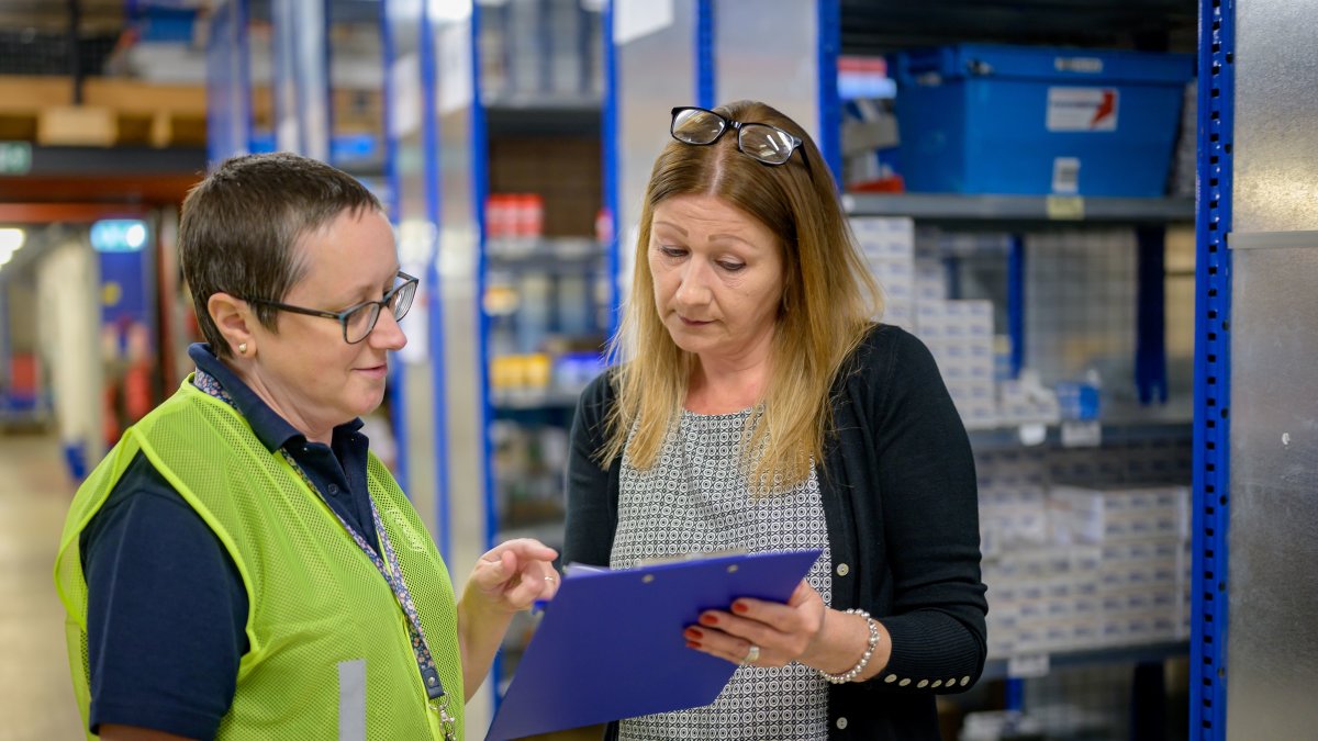 Two women reviewing an inventory checklist on a clipboard in a warehouse