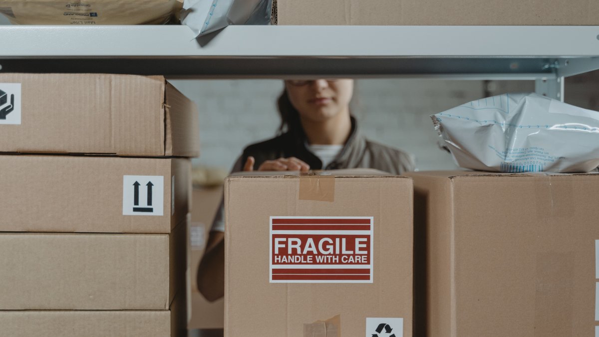 Person organizing fragile cardboard boxes in a warehouse setting